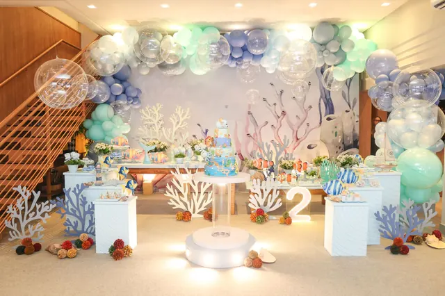 Decoração completa de festa infantil com tema fundo do mar, arco de balões e bolo no centro, no salão do Espaço Panda