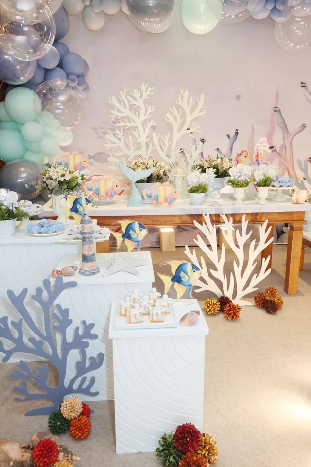 Mesa principal com corais, peixes e balões na decoração fundo do mar